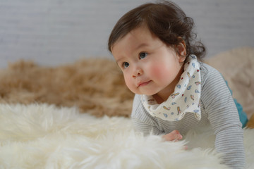 Sweet Beautiful baby girl playing on white furry. Baby girl concept.