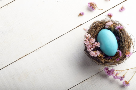 Rustic style painted easter egg in the nest on white table