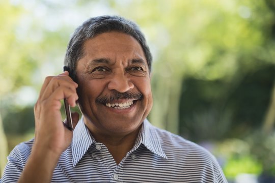Smiling senior man talking on mobile phone at porch