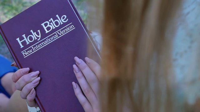 4k. Bible in hands of woman. Slider shot