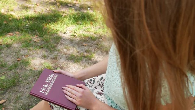 4k. Christian Bible in hands of woman. Slider shot