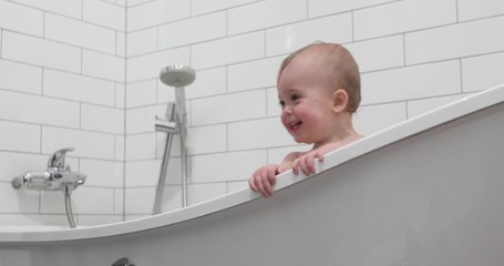 Lovely youth little boy kid standing in bathtub smiling and walking on bath in bathroom at home.