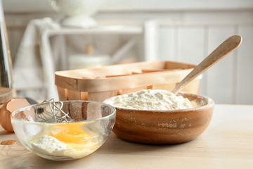 Bowls with flour and egg on table