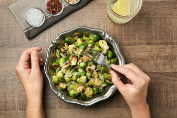 Woman eating roasted brussel sprouts at table