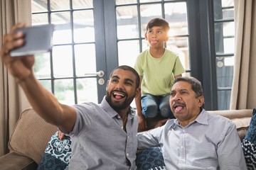 Happy multi-generation family making face while taking selfie at