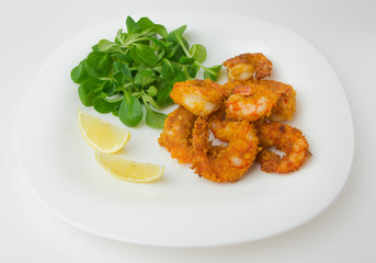 Fried shrimps on a plate. Prawns fried in breading on a white plate with salad and lemon.
