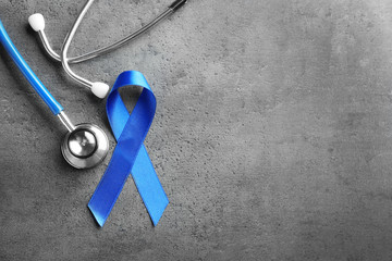 Blue ribbon and stethoscope on grey background. Cancer awareness concept