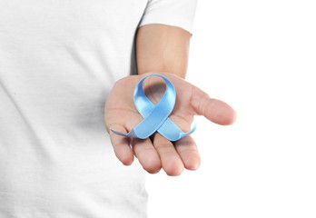 Young man holding blue ribbon on white background. Cancer awareness concept