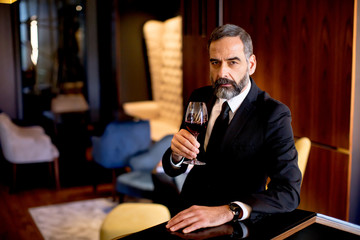 Handsome elegant businessman drinking red wine