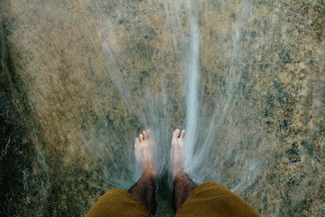 Men's foot standing on a rock at a waterfall
