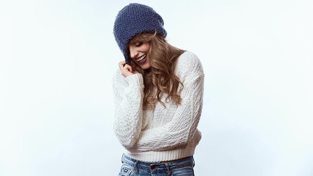 Portrait of sensual positive beautiful blond woman in sweater and blue hat isolated on white background in studio