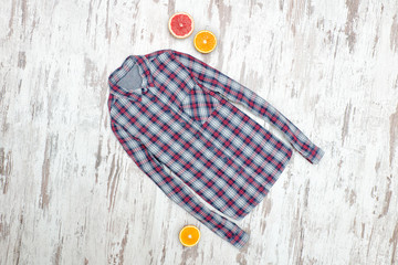 Checkered shirt on a wooden background, halves of citrus. Fashionable concept