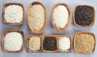 Various types of rice grain in wooden bowls.