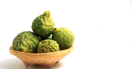 Obraz premium fresh bergamot fruit or the kaffir lime leaves in bamboo basket isolated on white background