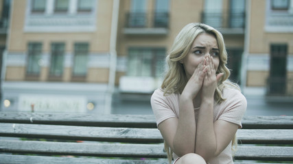 Fototapeta premium Sad young lady sitting alone and crying bitterly, relationship or health problem