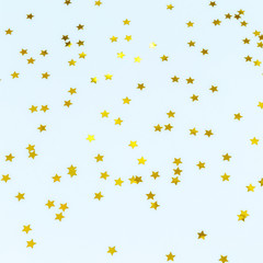Golden star sprinkles on blue. Festive holiday background. Celebration concept
