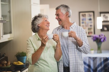 Happy senior couple looking at each in kitchen