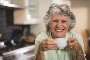 Happy senior woman holding cup at home