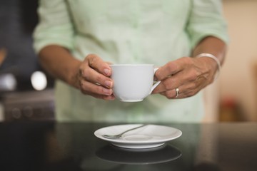 Mid section of woman holding cup