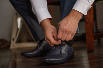 groom business man putting on smart shoes for wedding 
