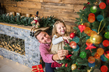 Christmas Eve, Dad and daughter decorate the Christmas tree at home.