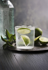 Drink acqua tonica, menta e lime con ghiaccio su tavolo scuro in legno