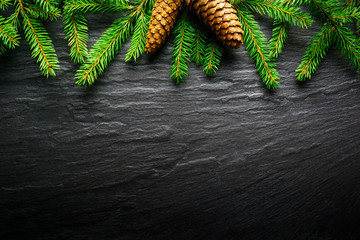 Christmas Background - Fir tree branch with pinecone on dark table. Top view and copy space