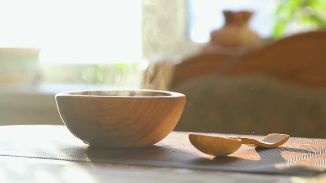 hot soup in a wooden plate. next to the table is a wooden spoon