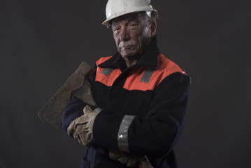Mature miner covered in coal dust holding an axe 
