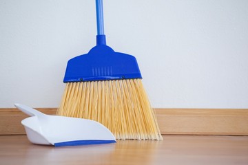 Dustpan and sweeping broom on wooden floor