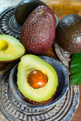 Healthy vegetarian food – green ripe avocado, new harvest, with leaves on stone plates with ornament