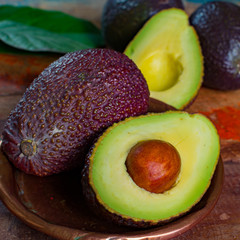Healthy vegetarian food – green ripe avocado, new harvest, with leaves on stone plates with ornament © barmalini