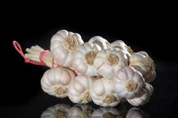 String of french pink garlic on old tin plate on black background
