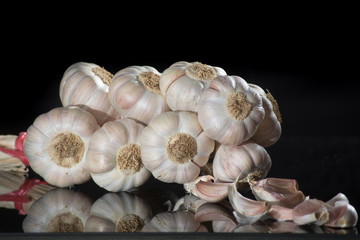 String of french pink garlic on old tin plate on black background