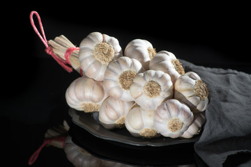 String of french pink garlic on old tin plate on black background