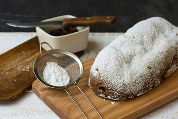 Homemade Whole Christmas Stollen on Wood Cutting Board Sieve with Powder Knife Ingredients Rustic Kitchen Interior