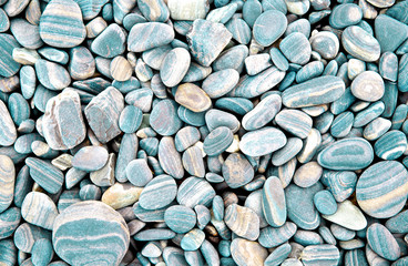 Abstract turquoise dry round stones background. At the beach. Sea pebbles and gravel style. Top view. Close up.