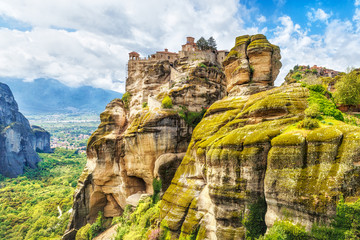Fototapeta na wymiar The Holy Monastery of Grand Meteoran in Meteora mountains, Thessaly, Greece. UNESCO World Heritage list. Temple complex on high rocks among the green trees. Iconic landmark in Greece.