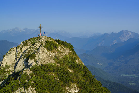 Hikers beside summit cross of Rossstein, Bavarian Prealps, Upper Bavaria, Bavaria, Germany