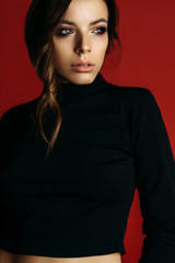 beautiful brunette girl posing in studio on red background