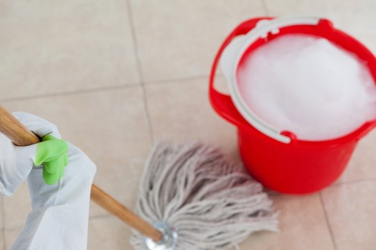 Bucket with foamy water and mopping the tile floor
