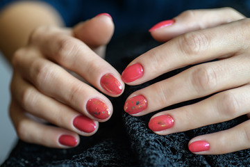 Woman with beautiful manicured red fingernails gracefully crossing her hands to display them to the viewer on a gray background in a fashion, glamour and beauty concept