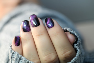 Beautiful nail polish in hand, purple nail art manicure, gray background