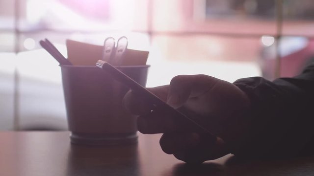 Close up of men hands use mobile phone and drinks coffee by the window in cafe. 3840x2160