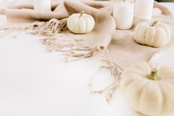 White pumpkins and candles on beige plaid. Autumn or winter composition.