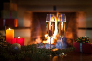 Two glasses with champagne in front of the fireplace. New Year. Christmas.