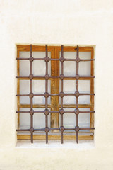 Metal grille with a geometric pattern on an old wooden window. Protective architectural element