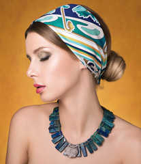Beauty portrait of young beautiful woman with closed eyes. Necklace and hair with a headscarf