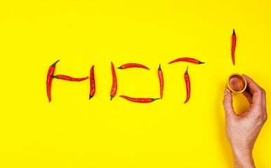A man holds a glass of spirits surrounded by spicy chili peppers on a yellow background.