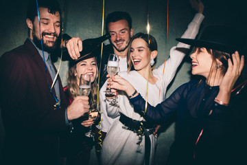 Group of happy friends drinking champagne and celebrating New Year. New year party. Birthday party  - obrazy, fototapety, plakaty